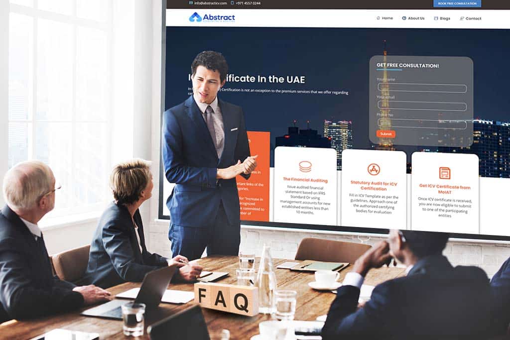 A man in a business suit is giving a presentation to three seated colleagues. They are in a conference room, looking at a large screen displaying a website titled "Abstract" with information on VAT services in the UAE. A "Get Free Consultation" form is visible on the screen.
