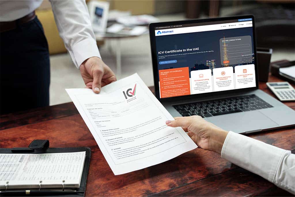 Two people exchange an ICV (In-Country Value) certificate across a wooden desk. A laptop is open on the desk, displaying a website detailing the process of obtaining ICV certification in the UAE. An open binder and a calculator are also on the desk.